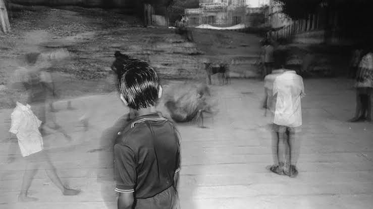 Black and white blurry photography of young children standing outdoors in a suburban setting.