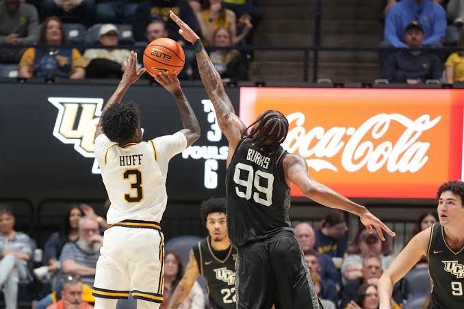 West Virginia Mountaineers basketball players compete on court during a Big 12 conference game.