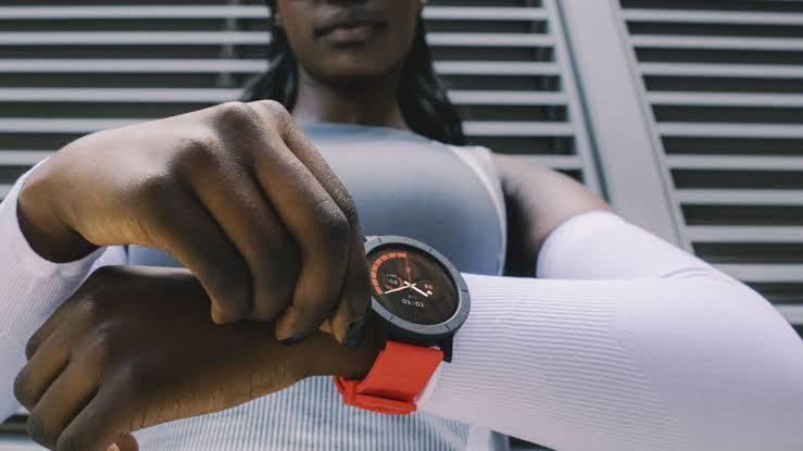 A woman wearing the orange CMF Watch 3 Pro smartwatch on her wrist during an outdoor activity.
