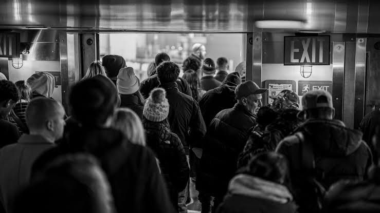 A crowded hallway leading to a small exit door symbolizing liquidity constraints in the bitcoin futures market.