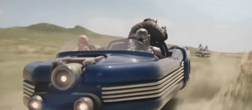 The Mandalorian and Grogu riding a speeder during a chase sequence in a desert landscape.