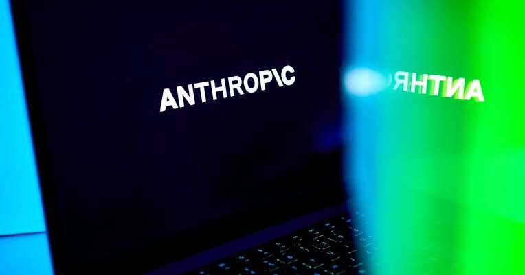 Anthropic logo visible on a laptop screen while a researcher prepares to step away from their desk.