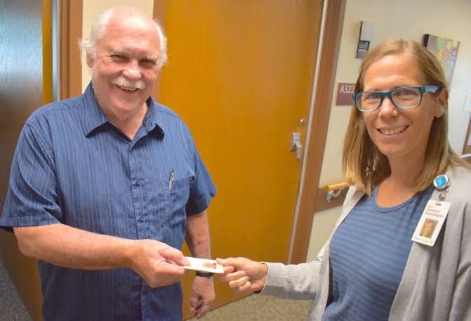 Greg Omori hands his name tag to Betsy Anderson at the New Ulm Medical Center following his retirement.