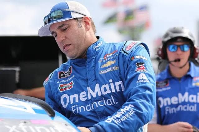 Elliott Sadler standing in front of a race car during a past NASCAR event in Virginia.