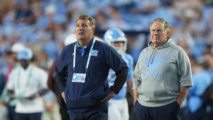 Michael Lombardi speaking with head coach Bill Belichick on the sidelines at Kenan Memorial Stadium in Chapel Hill.