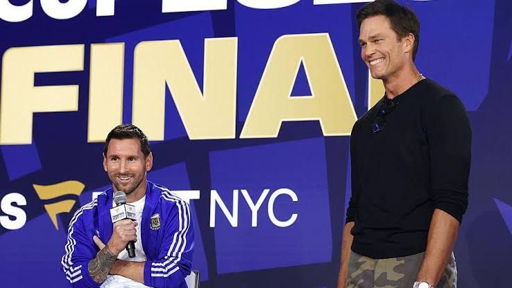 Lionel Messi and Tom Brady speaking on stage at a sports event ahead of the 2026 World Cup final.