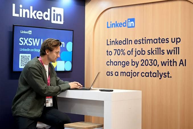 A person working at a desk with a LinkedIn feed displayed on a computer screen.