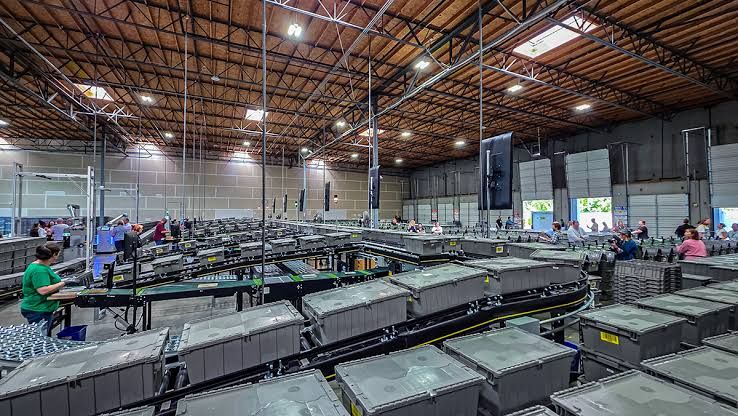 Robotic arm destacking library book totes at the new King County Library System sorting facility in Renton, Washington.