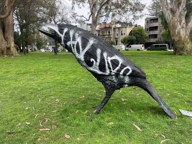 One of two large bronze crow sculptures in San Francisco’s Panhandle standing on grass after being cleaned of graffiti.