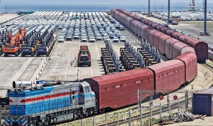 Heavy equipment and cars prepared for rail shipment in Yantai, Shandong province, during June 2026.