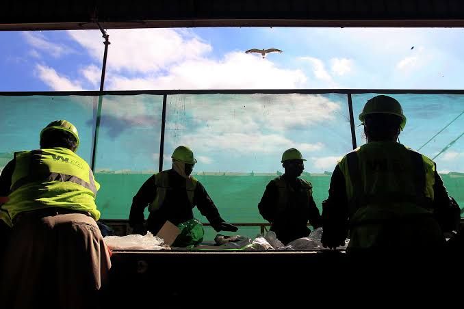 Employees separate recyclable items from trash at a Waste Management facility in San Leandro.