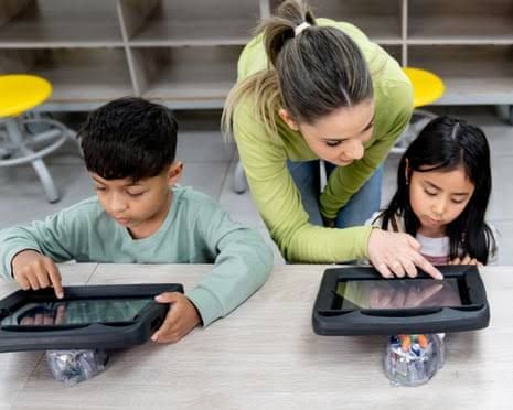 A teacher guides students using tablets in a classroom to demonstrate integrated technology.