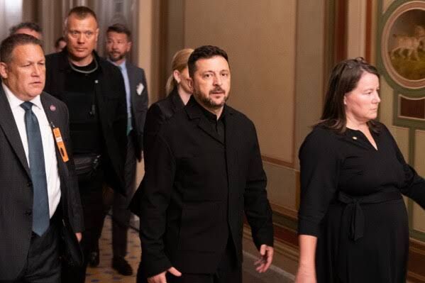 Ukrainian President Volodymyr Zelenskyy walks through the U.S. Capitol with senators while visiting for a sanctions vote.