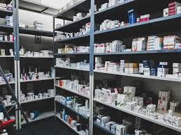Hospital staff and pharmacists reviewing medication supplies in a secure facility setting.