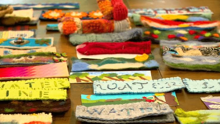 Local Cloth studio members work on fiber art strips to mark the flood level from Hurricane Helene in Asheville, NC.